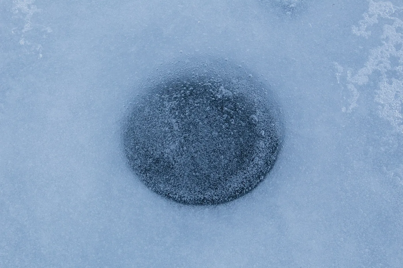 Un agujero redondo en una capa de hielo cubierta de nieve, visto desde arriba
